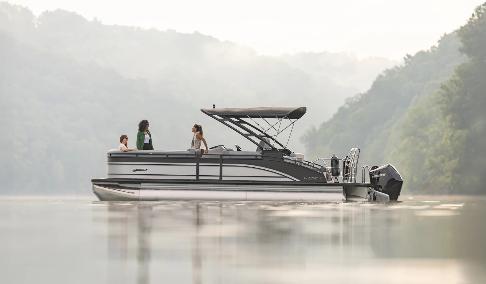 Harris Solstice 250 SL cruising across a calm mountain lake