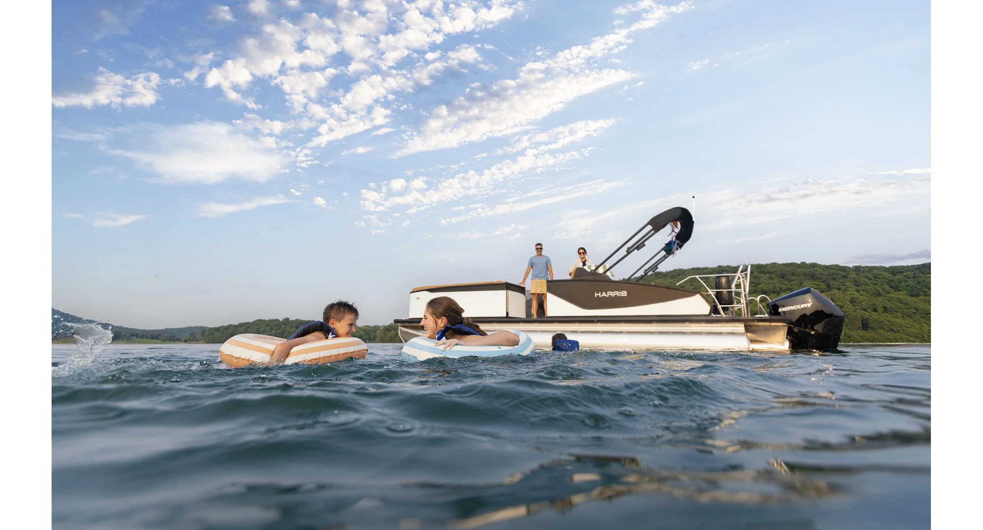 Family swimming beside a Harris Sunliner pontoon on a Tennessee lake